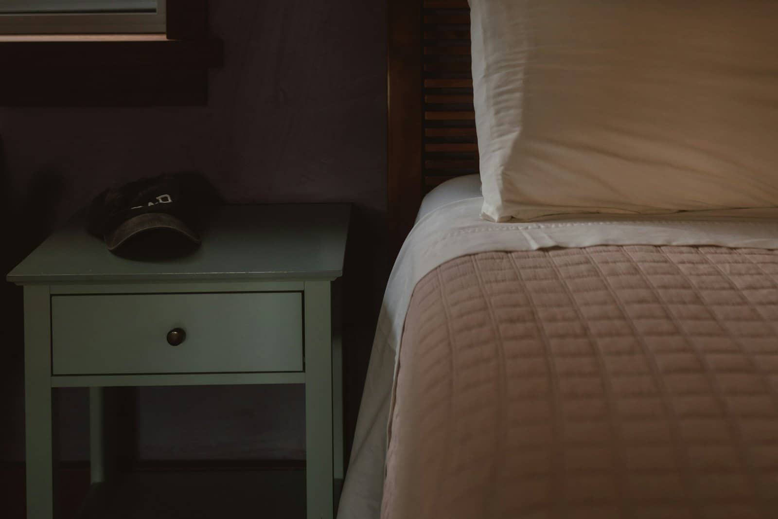 A dark bedroom with a bed and a bedside table