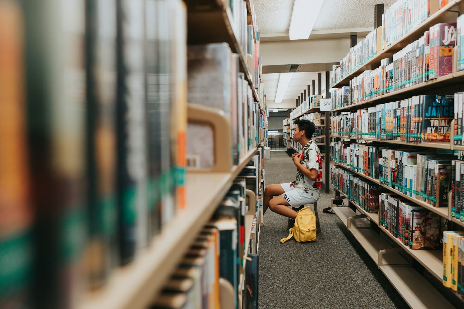 A student reading between library shelves